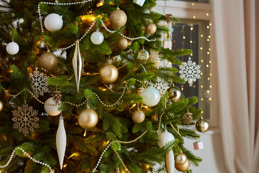 Vianočný stromček s ozdobami v zlatej, striebornej a bielej farbe.