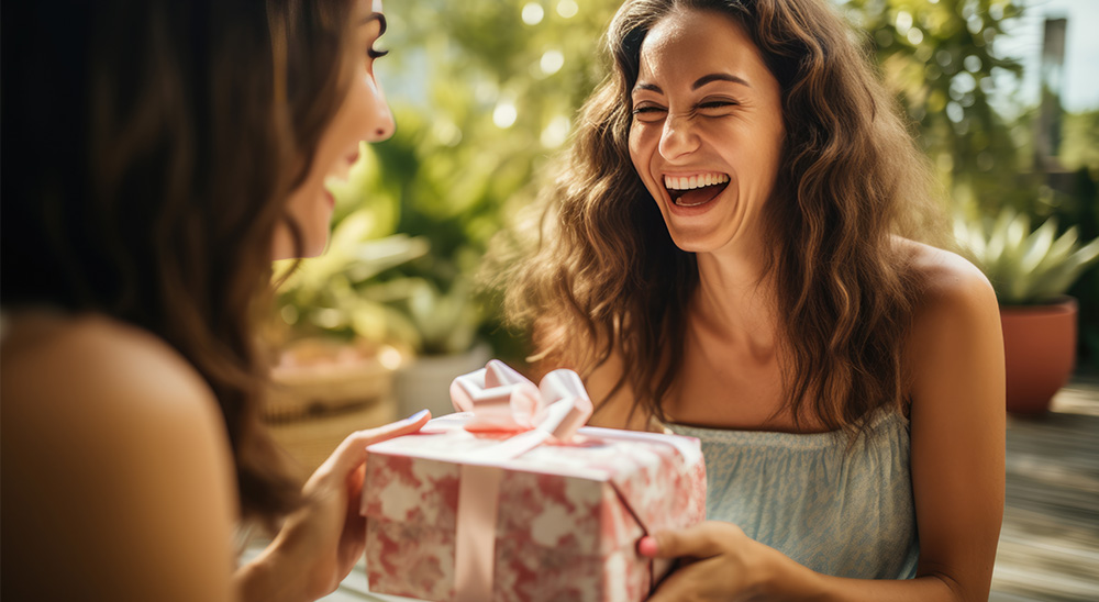 Usmievajúca sa žena daruje darček priateľkei.