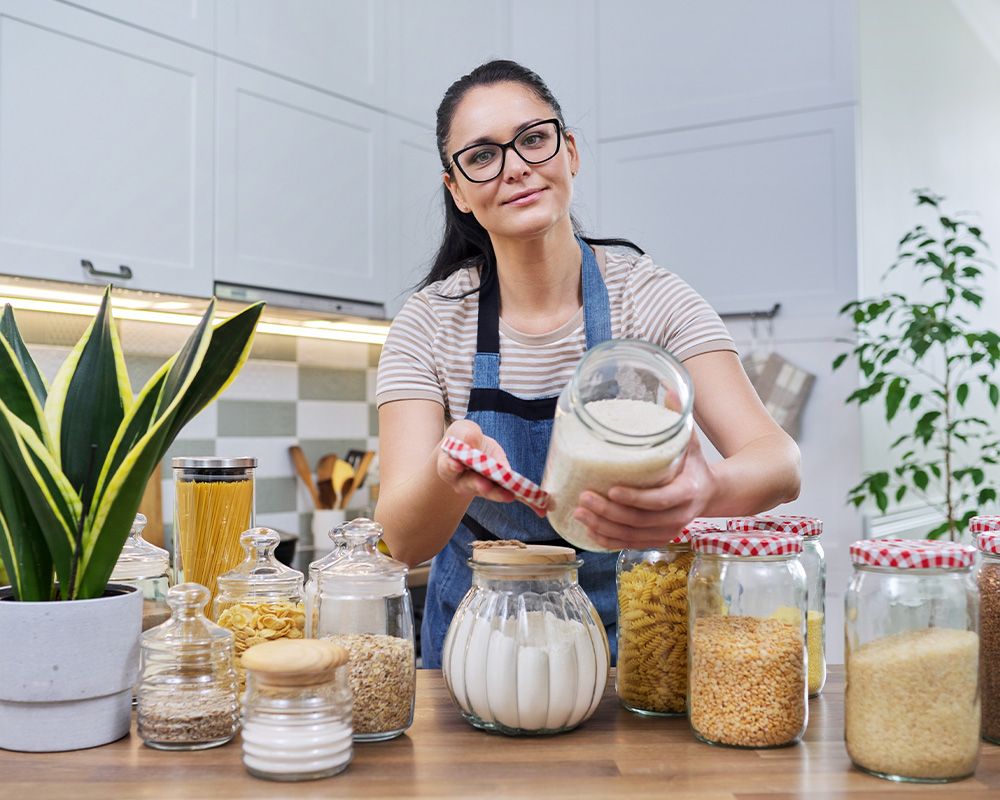 Žena v kuchyni ukazuje poháre na uschovávanie suchých potravín
