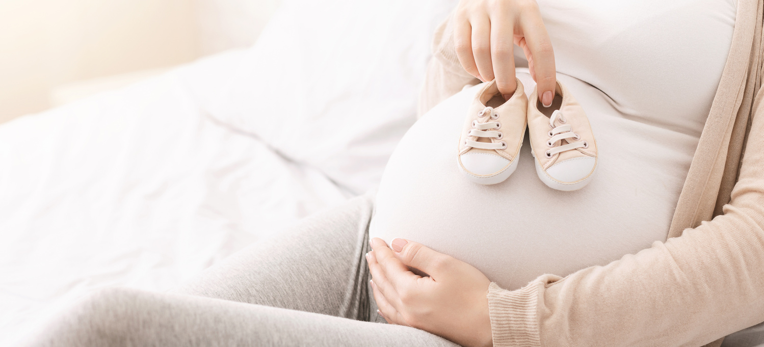 Tehotná žena drží dojčenské topánočky na bruchu