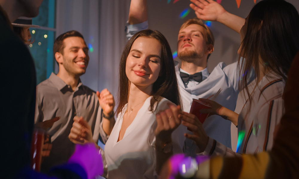 Skupina ľudí tancuje na párty, medzi nimi je žena, ktorá si užíva hudbu.