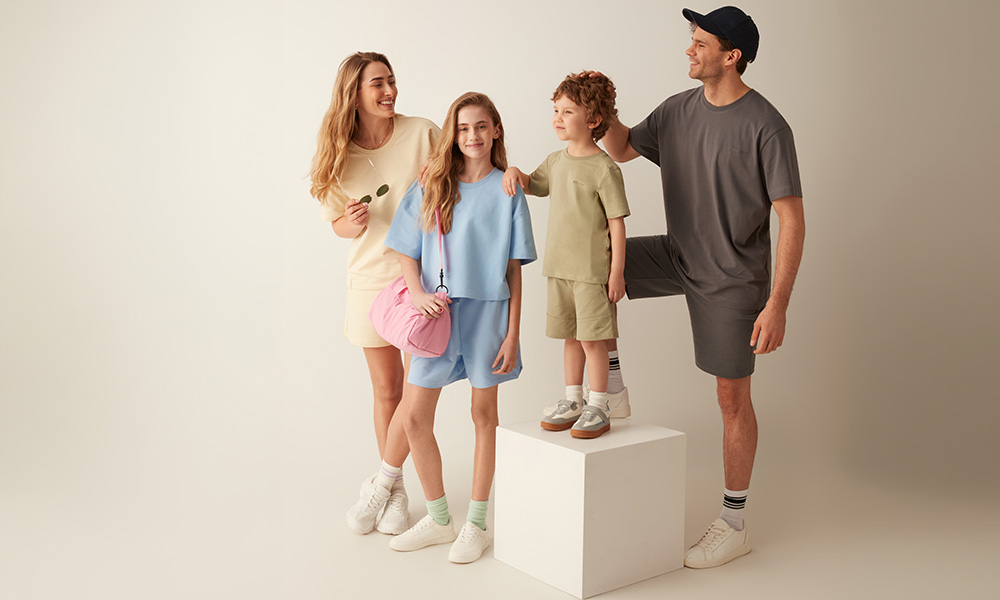 Rodina v pastelovom oblečení pózuje spolu na svetlom pozadí.